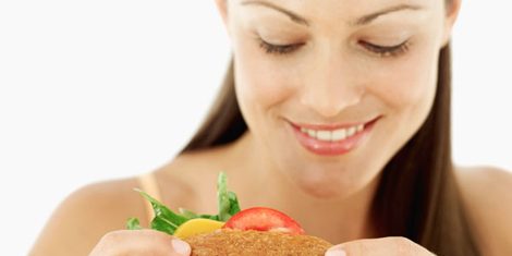 Portrait of a young woman smiling holding a sandwich